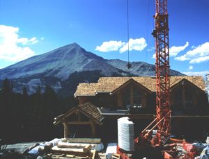 mountain in background with large residential home in middle ground and a crane in the foreground